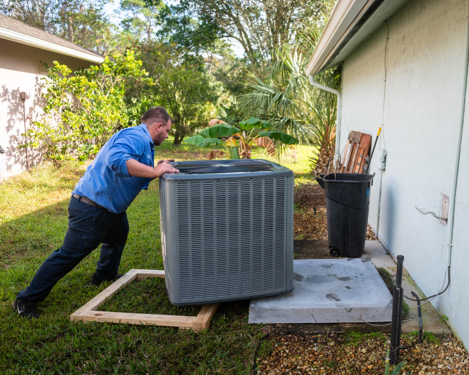 Sunshine State installer setting a new Amana condenser onto a fresh concrete pad