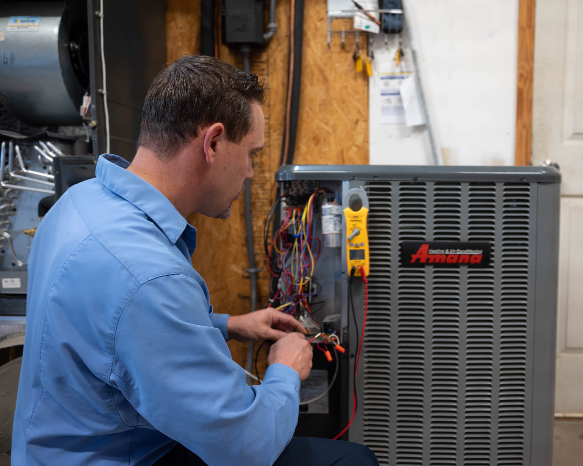 Sunshine State technician servicing the electrical panel of an indoor heating unit