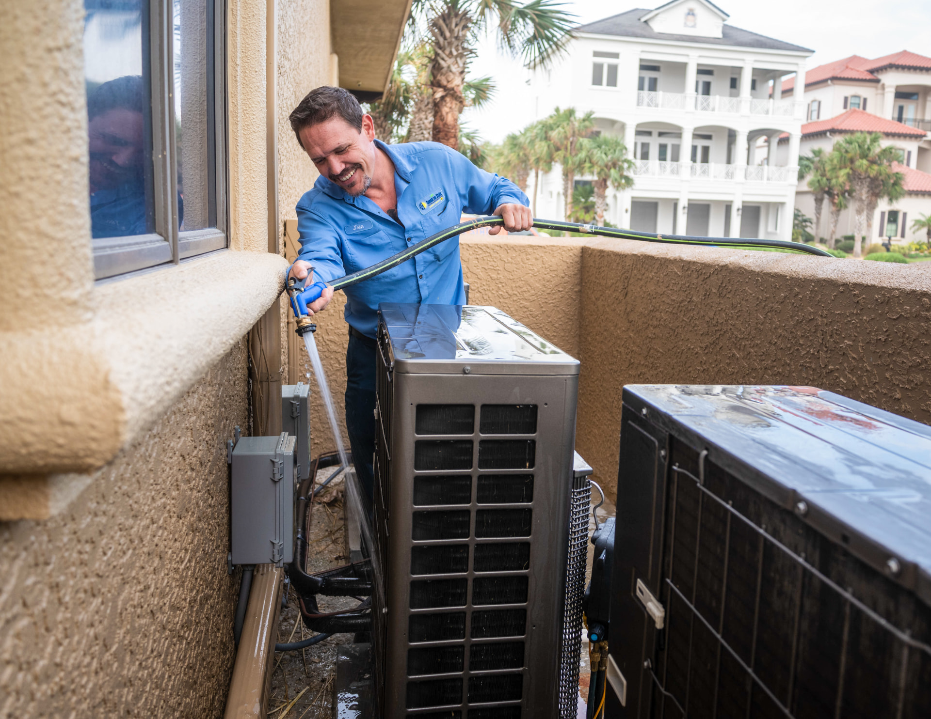 Sunshine State technician rinsing condenser coils during a seasonal maintenance tune-up