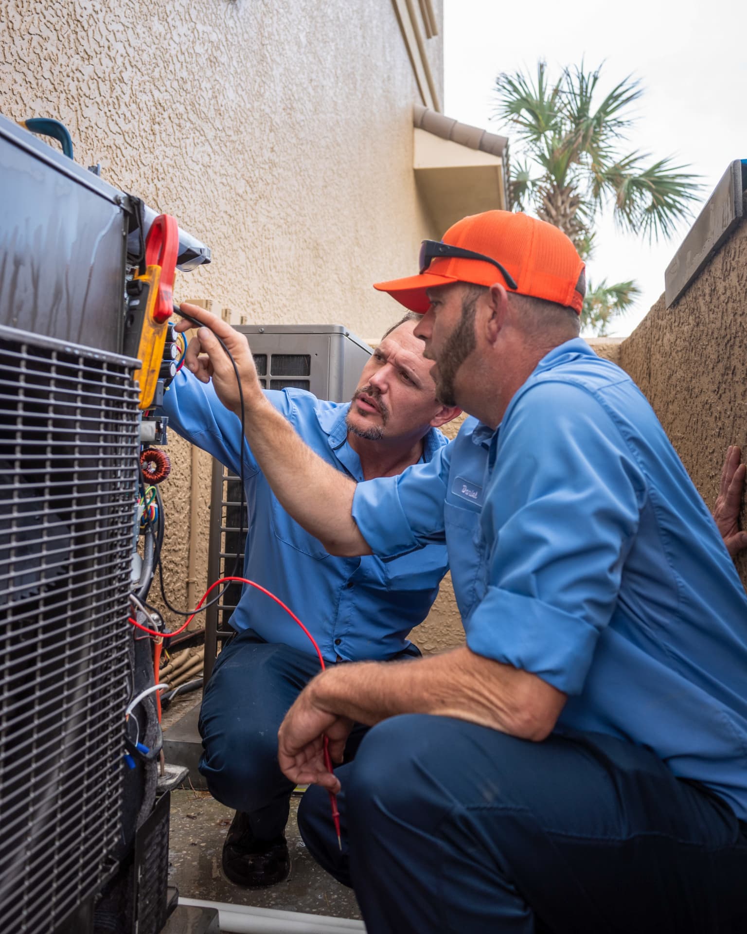 Sunshine State technicians testing air conditioner wiring with a clamp meter during a repair call